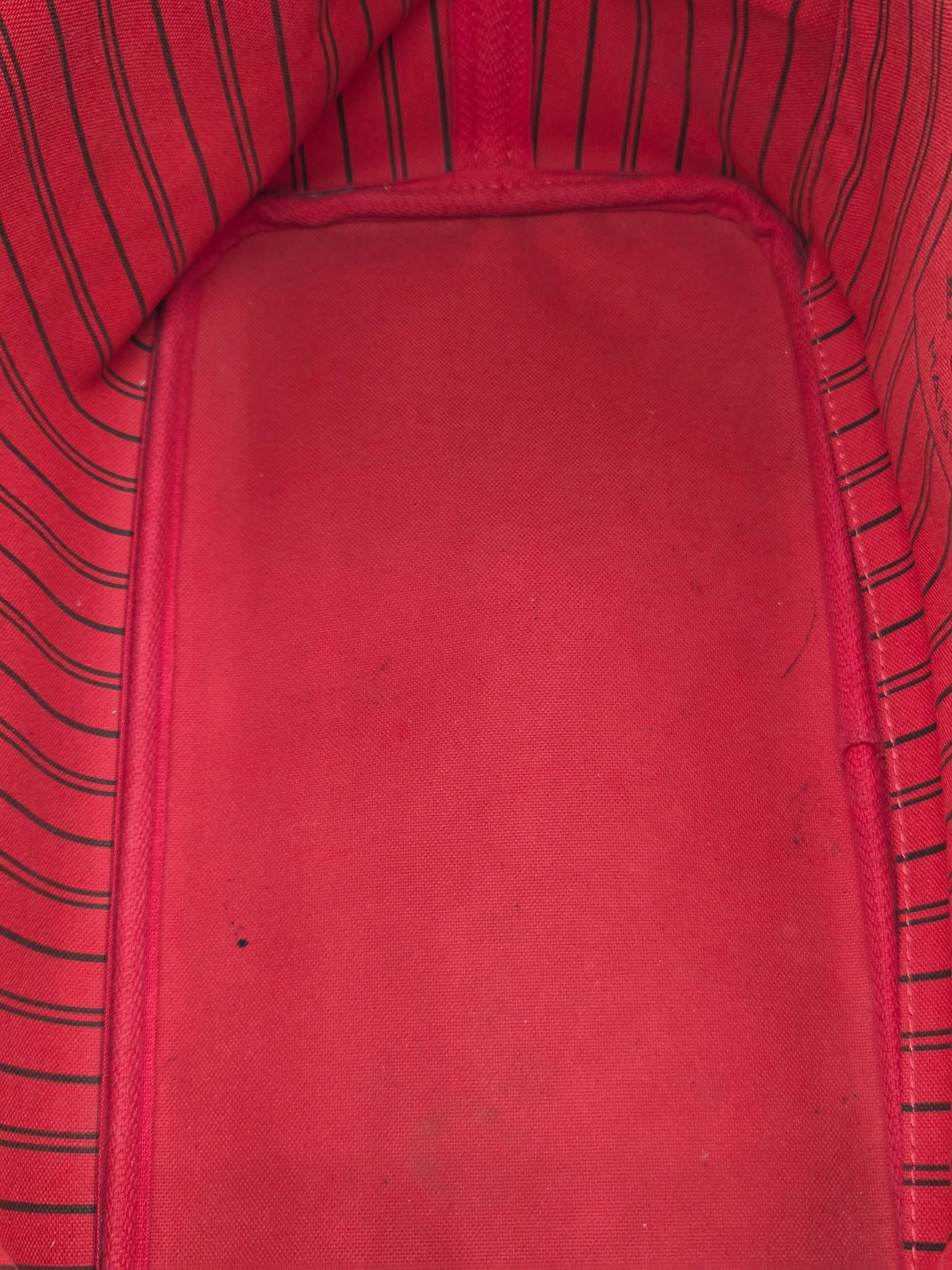 Close-up of a red fabric interior with a smooth central panel and striped red-and-black fabric lining along the edges.