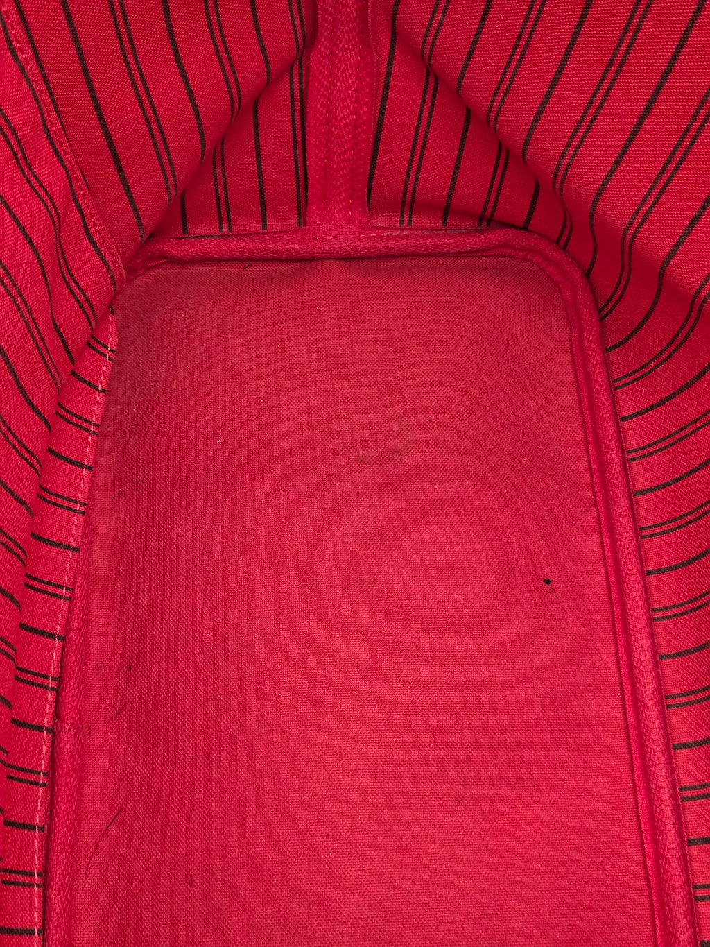 Close-up of a red fabric interior with black pinstripes along the sides and a solid red padded center panel.
