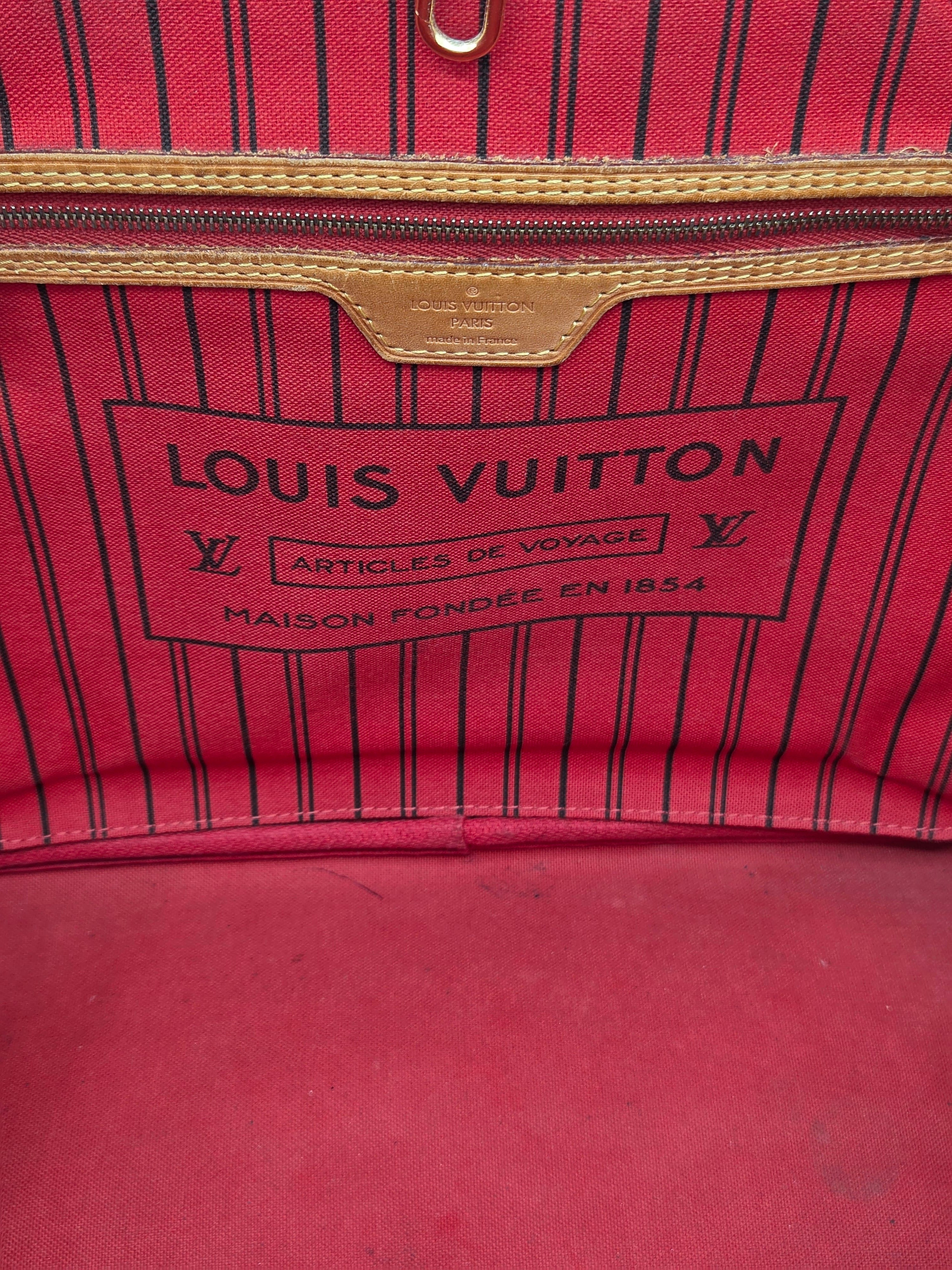 Close-up of a Louis Vuitton red and black pinstriped fabric bag interior, showing the brand label and zipper trim.
