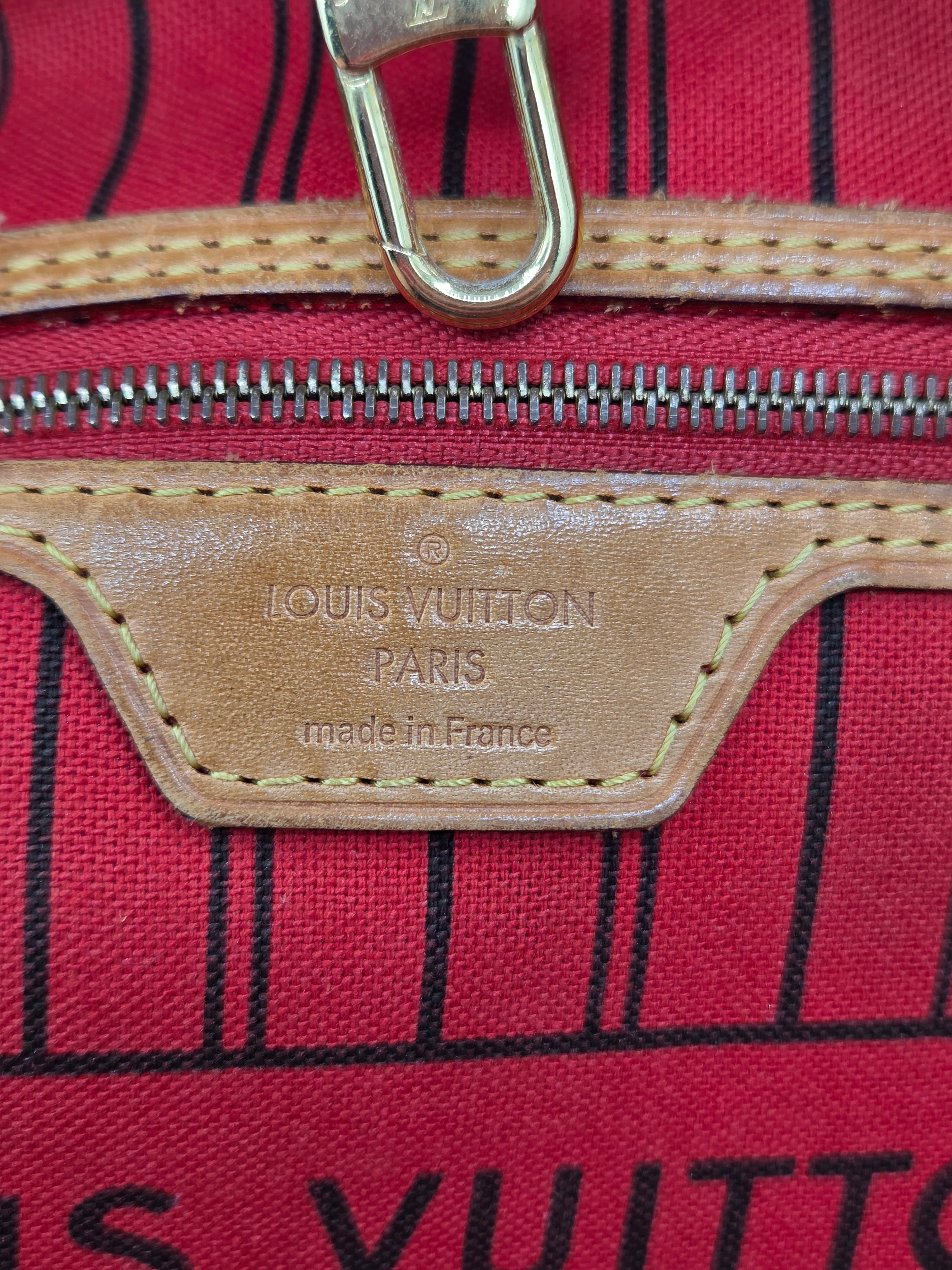 Close-up of a Louis Vuitton bag featuring a red canvas body with black stripes, tan leather zipper trim, and a metal D-ring closure. The embossed leather patch reads 'LOUIS VUITTON PARIS made in France'.