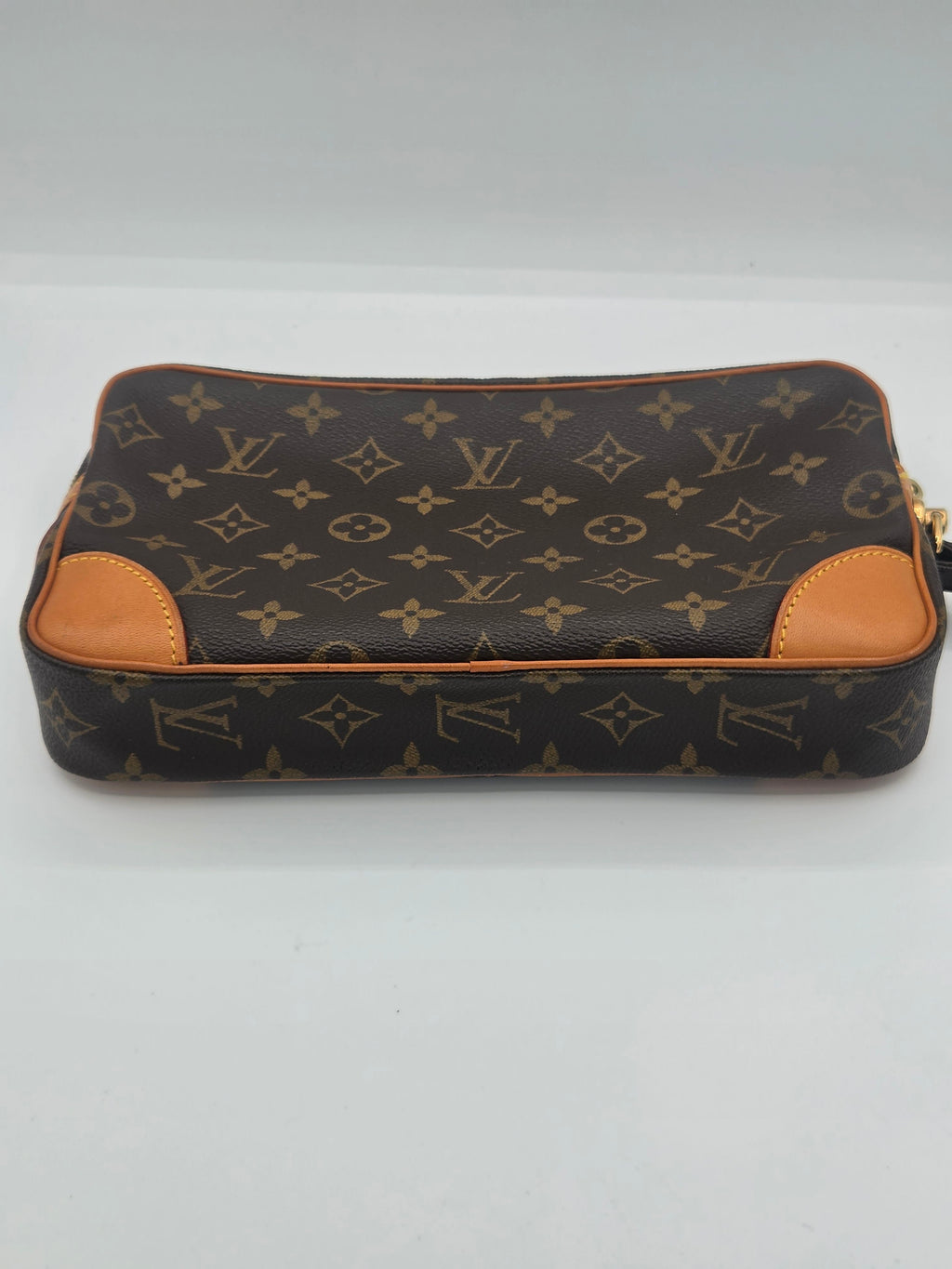 A Louis Vuitton monogram canvas pouch with tan leather trim and gold-tone hardware, photographed on a plain light background.