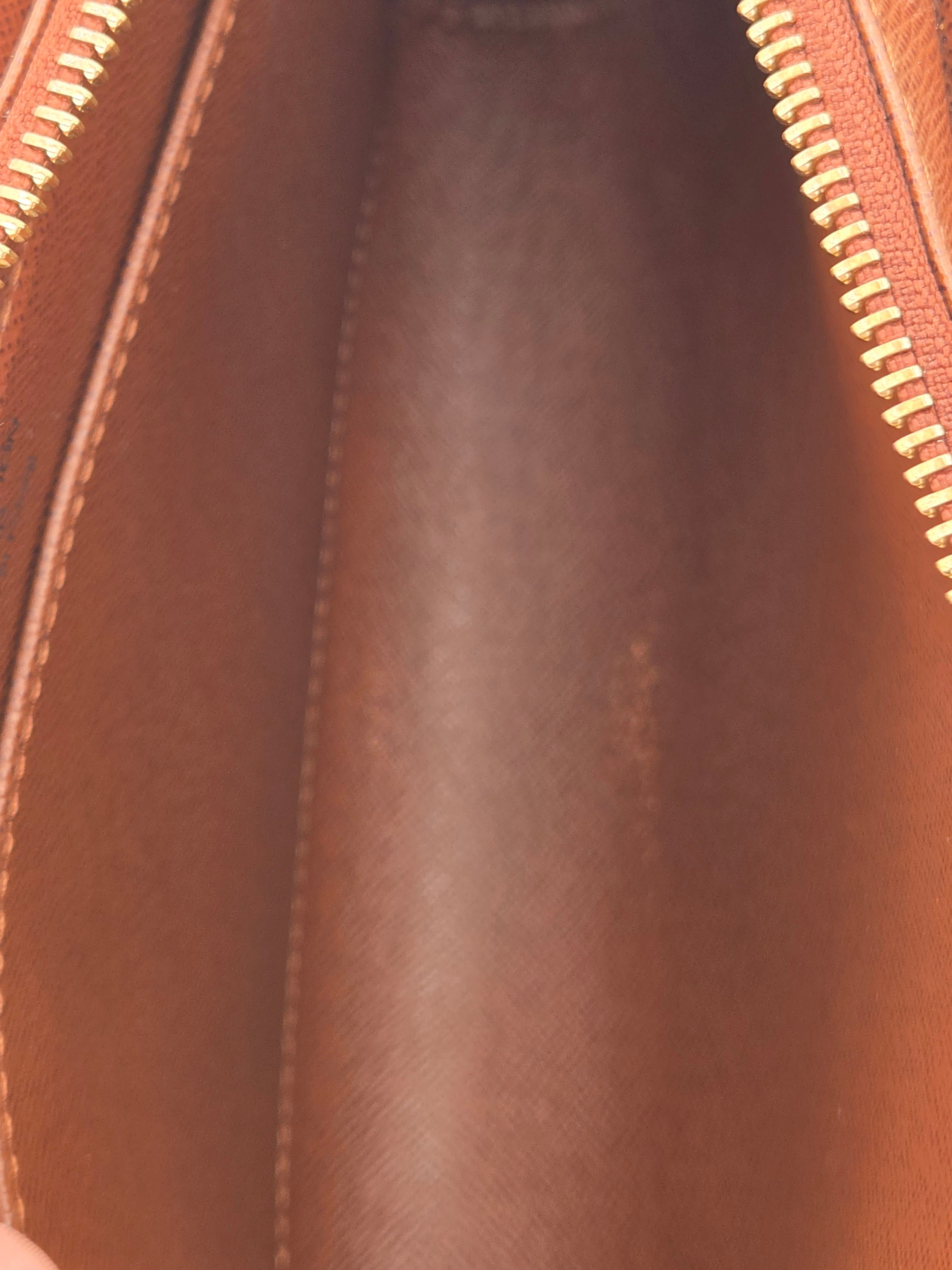 Close-up of the interior of a brown leather zippered pouch or bag, showing the smooth brown lining, stitched edges, and gold-tone zipper teeth.