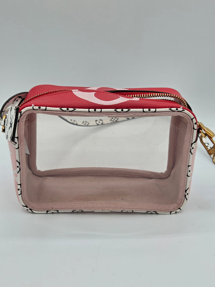 A small rectangular cosmetic pouch with a clear front window, a red top flap, and a black-and-white patterned body, shown on a light gray background.