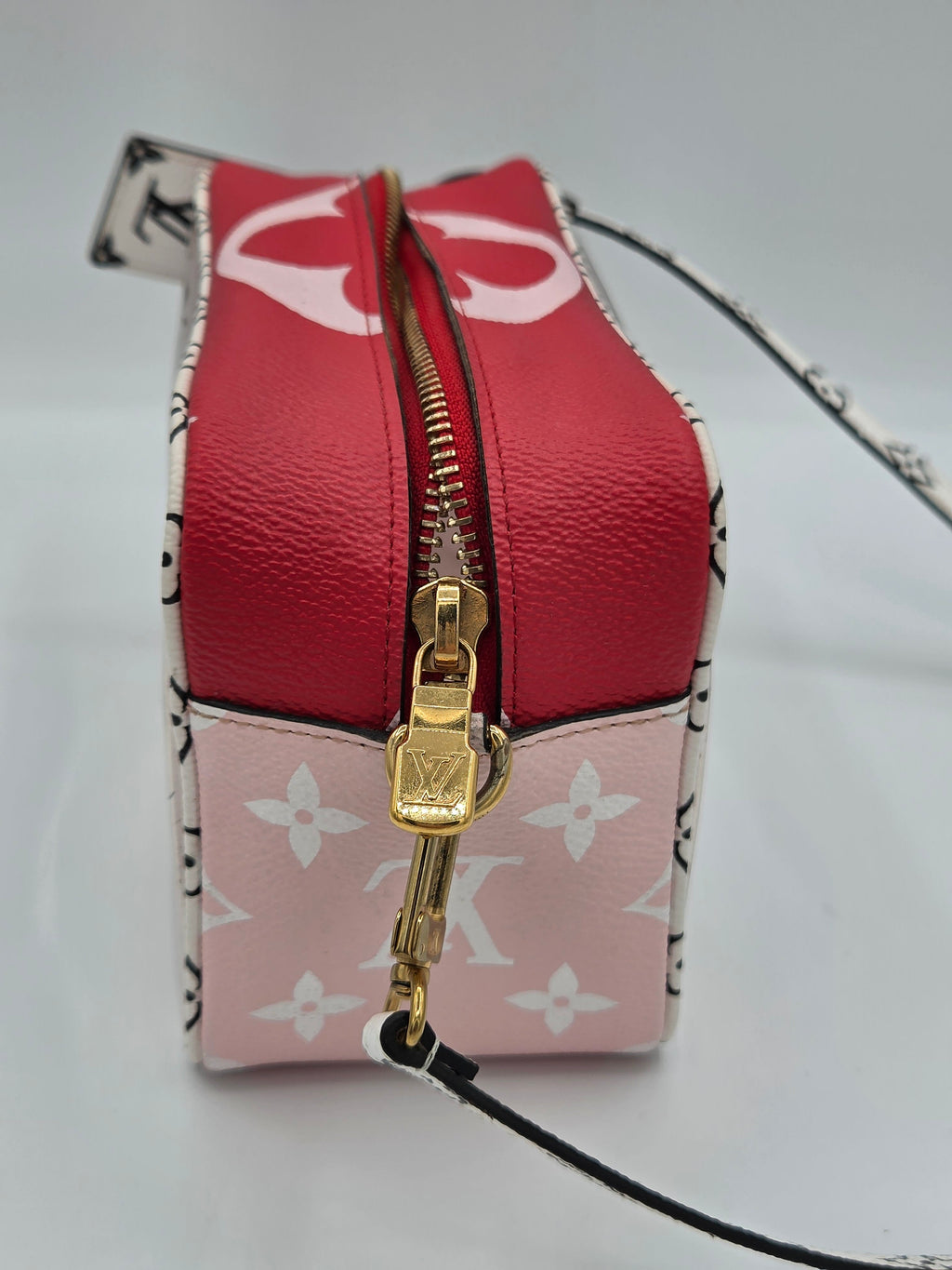 A Louis Vuitton zippered pouch in red and pink monogram canvas, featuring a gold-tone zipper and lock, photographed on a light gray background.