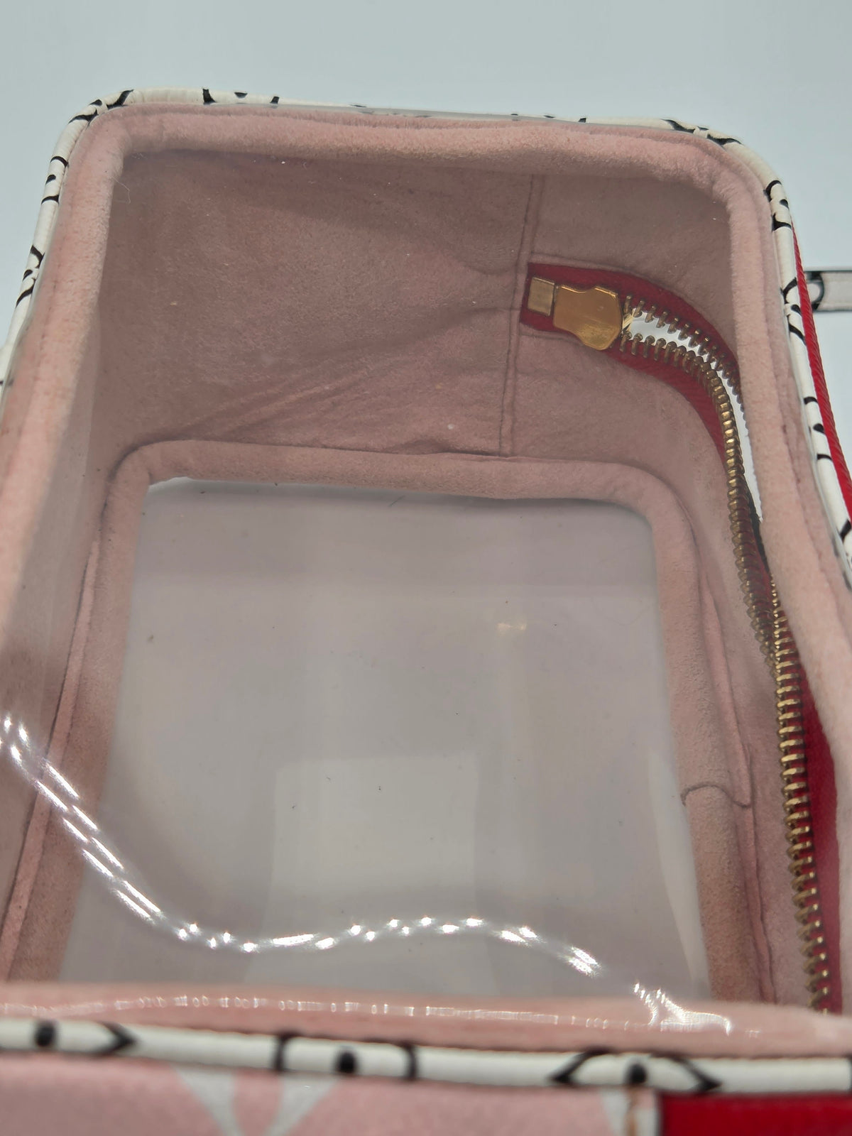 Close-up of a pink zippered organizer or case with a clear plastic window on the front, shown against a light gray background.