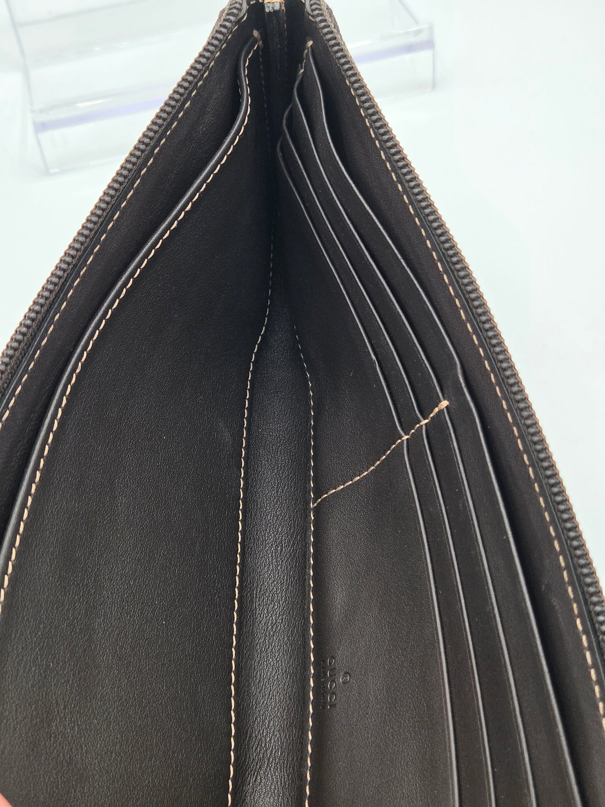 Close-up of the interior of a dark brown leather wallet or card holder, showing multiple card slots, interior stitching, and the zipper edge.