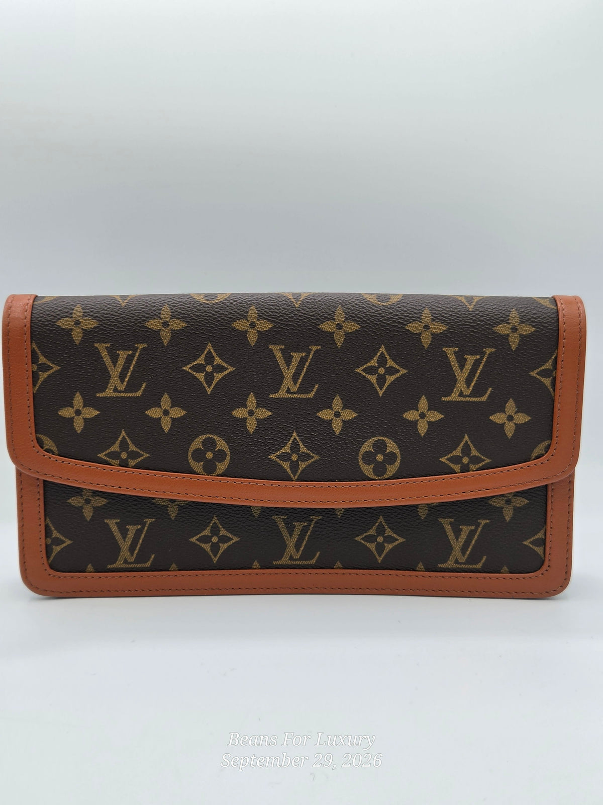 A Louis Vuitton monogram wallet in dark brown coated canvas with tan leather trim, shown against a light gray background.