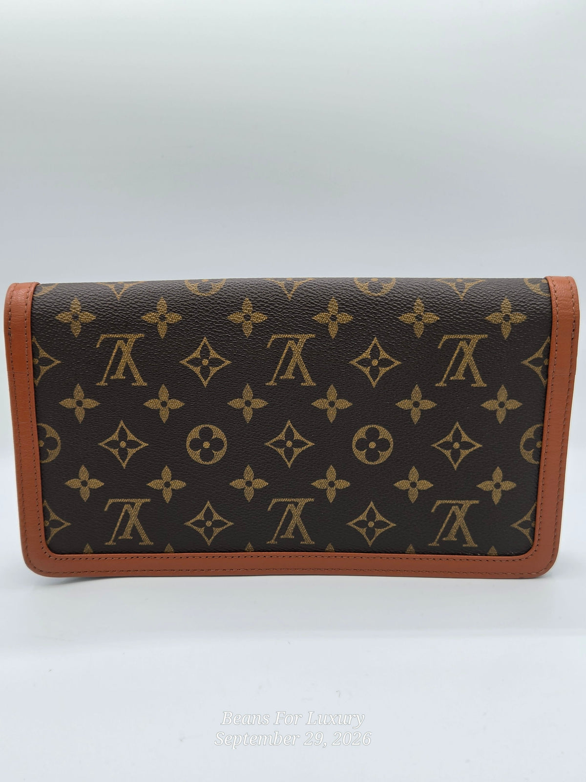 A Louis Vuitton monogram wallet in brown coated canvas with tan leather trim, shown against a light gray background.