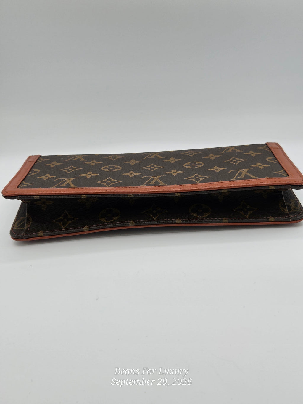 A Louis Vuitton monogram wallet in brown coated canvas with tan leather trim, shown open on a light gray background.
