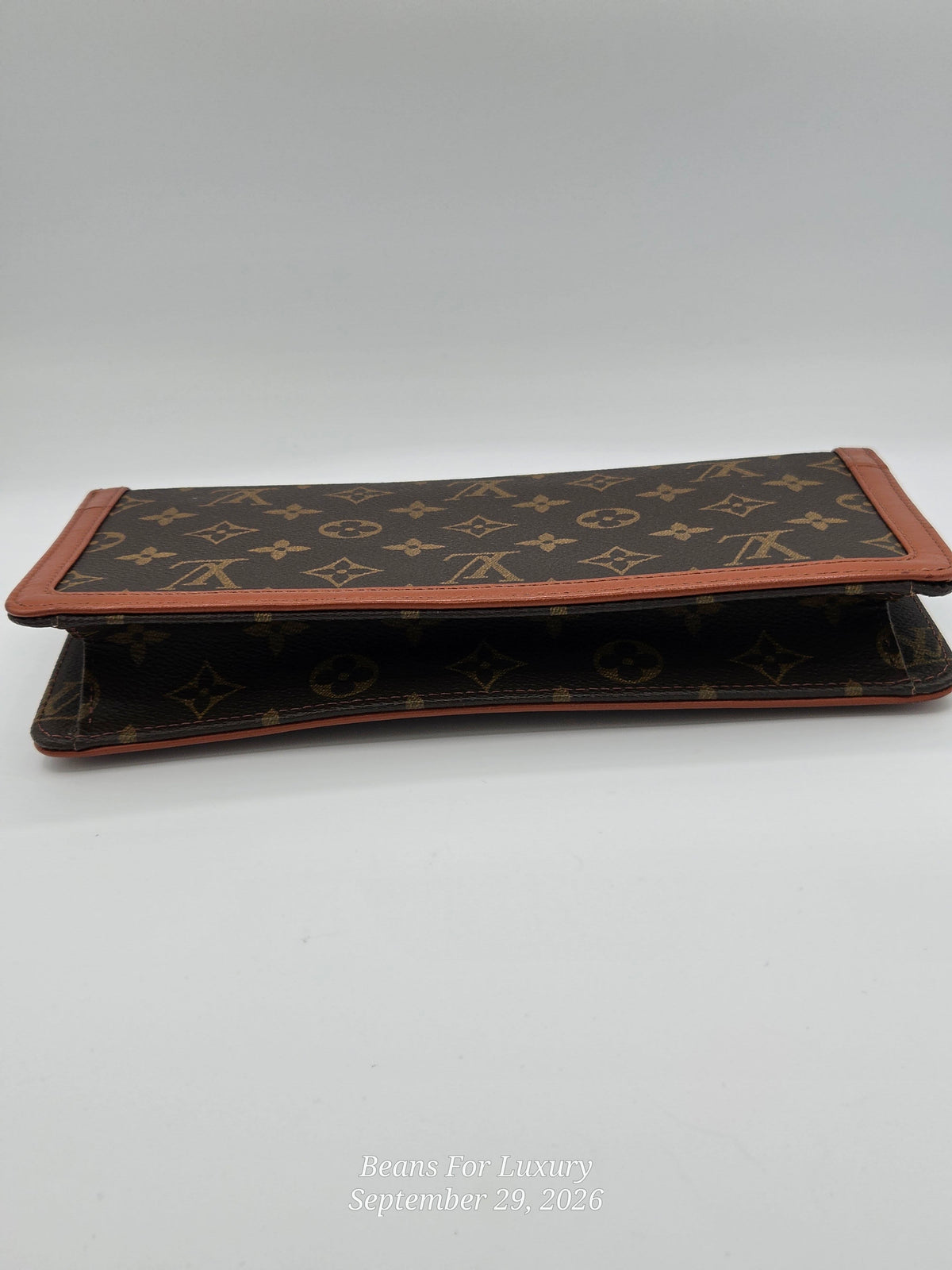 A Louis Vuitton monogram wallet in brown coated canvas with tan leather trim, shown open on a light gray background.
