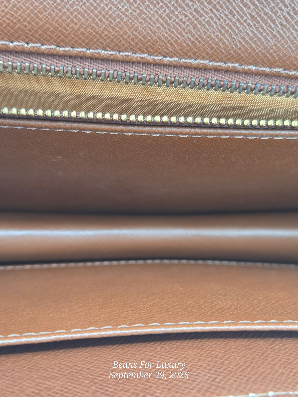 Close-up of a brown textured leather interior with a gold-toned zipper and white stitching. A small watermark at the bottom reads Beans For Luxury September 29, 2026.