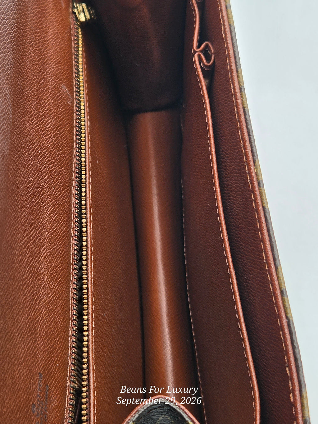 Close-up detail of a brown leather bag interior showing a gold zipper, stitched pocket, and smooth brown lining, with a small watermark reading Beans For Luxury September 25 2026.