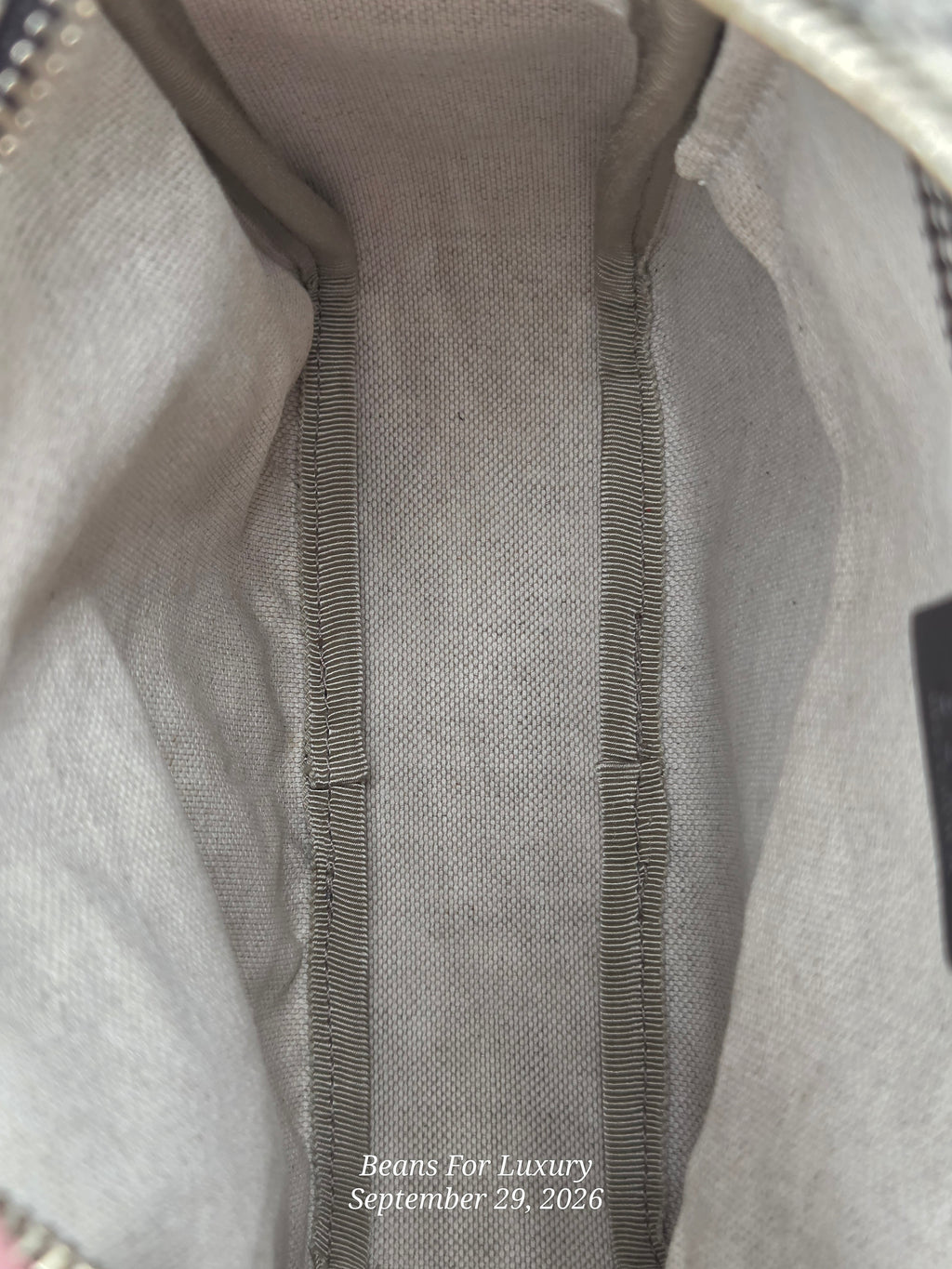 Close-up of the interior lining of a beige or light taupe fabric bag, showing the stitched interior edge and zipper tape. A small watermark at the bottom reads 'Beans For Luxury September 29, 2026'.