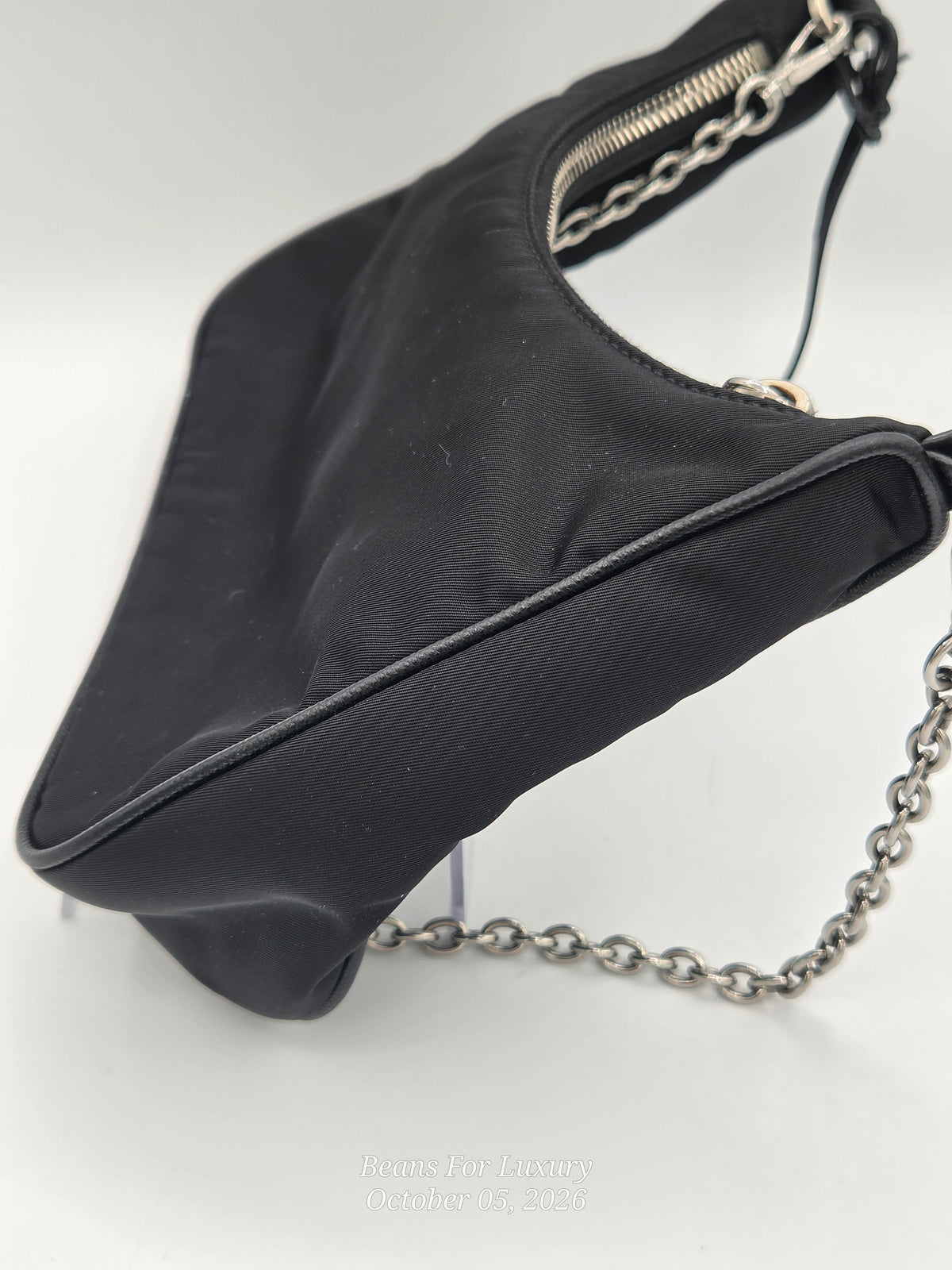 A black nylon shoulder bag with silver-tone chain strap and zipper details, photographed on a white background.