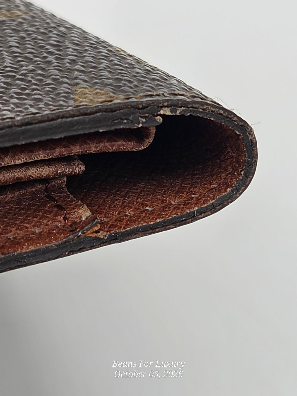 A close-up of a vintage brown textured leather wallet corner showing the aged, worn interior lining and edges against a light gray background.
