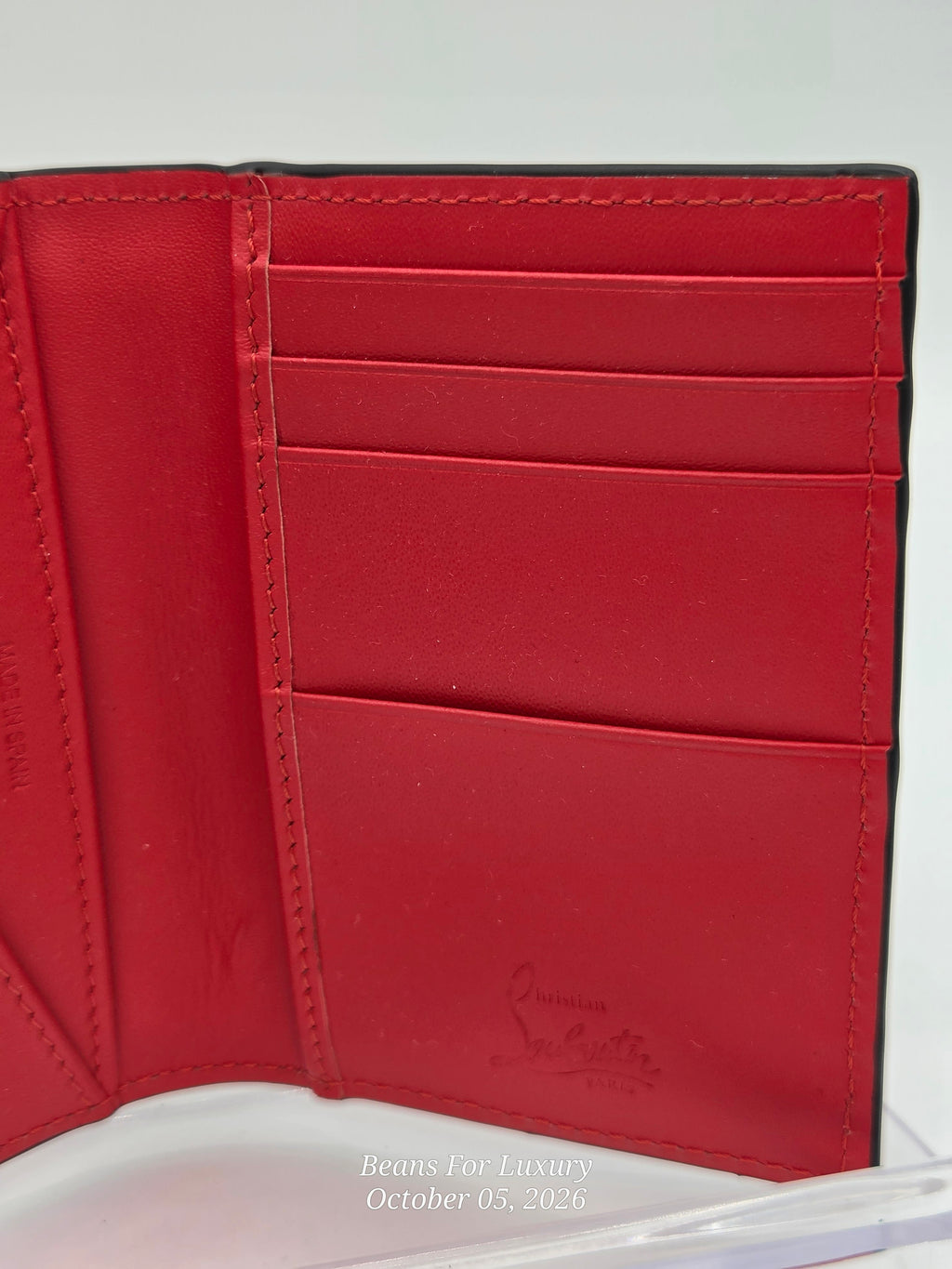 A close-up of an open red leather wallet showing the interior card slots and stitching, photographed against a light background.