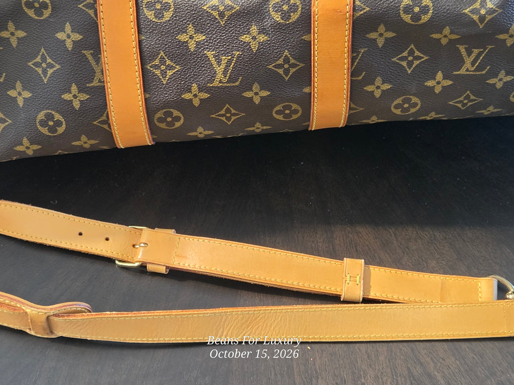 Louis Vuitton monogram canvas duffel bag with tan leather trim and strap, shown on a dark wooden surface.