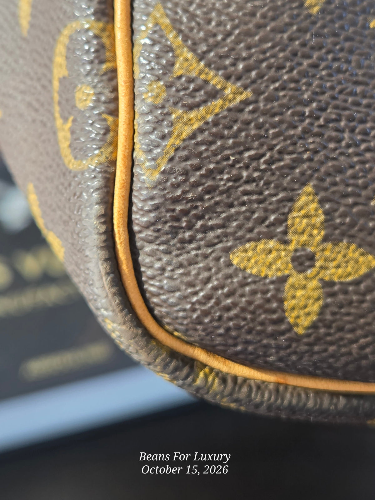 Close-up of a brown coated canvas item with the yellow Louis Vuitton monogram pattern and a thin tan leather piping edge. A watermark at the bottom reads 'Beans For Luxury October 15, 2026'.