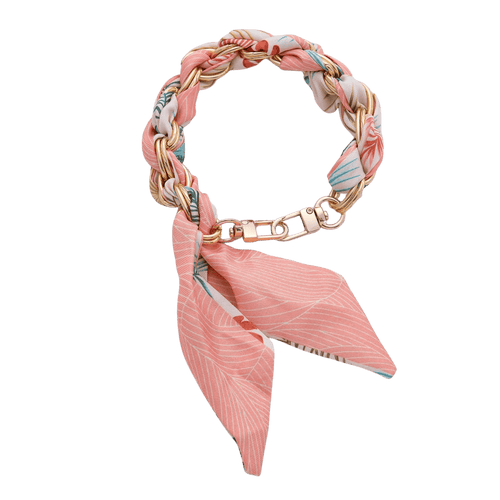 Bracelet with pink fabric wrap and gold chain on a green background