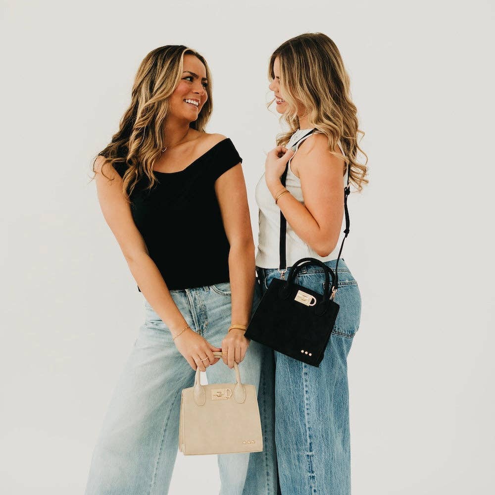 Two women holding handbags against a plain background