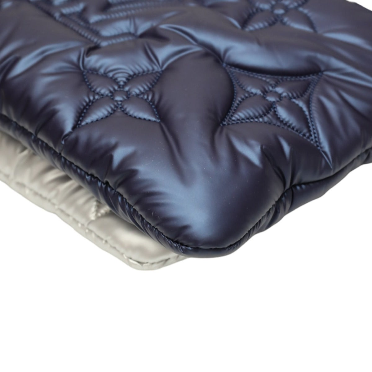 Close-up of a quilted fabric surface with a diamond pattern on a white background