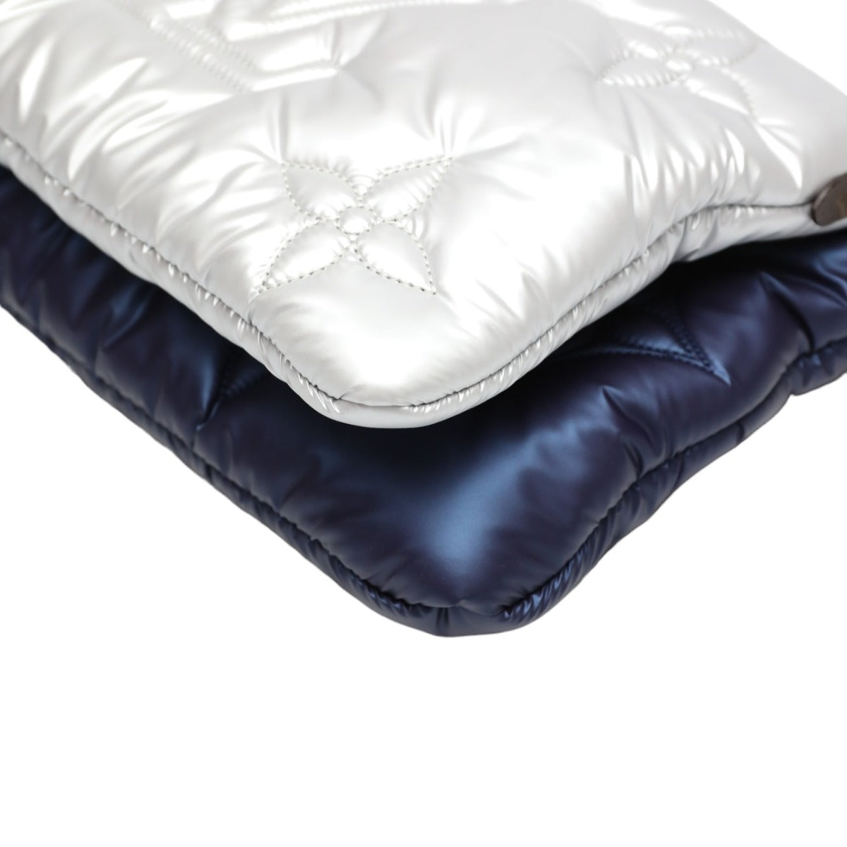 Two folded puffer jackets, one white and one navy, on a white background.