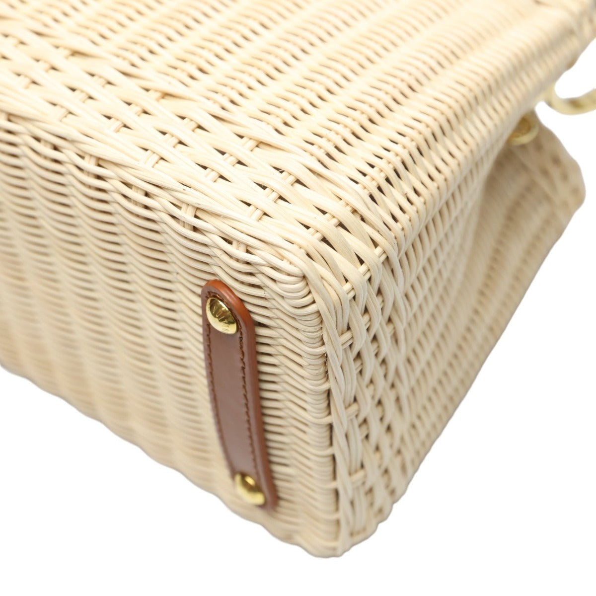 Close-up of a woven handbag with a leather strap and gold clasp on a white background
