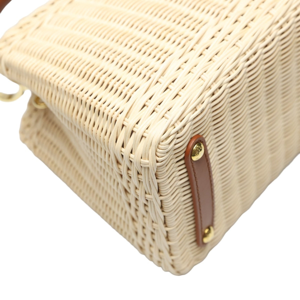 Close-up of a woven handbag with a brown strap on a white background
