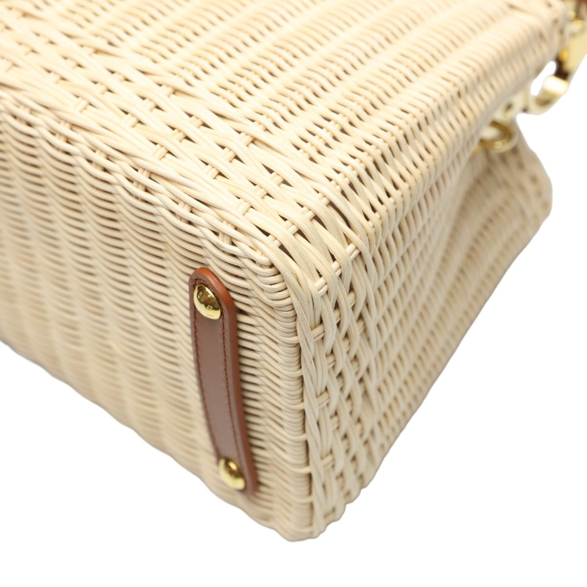 Close-up of a woven handbag with a brown strap and gold hardware on a white background