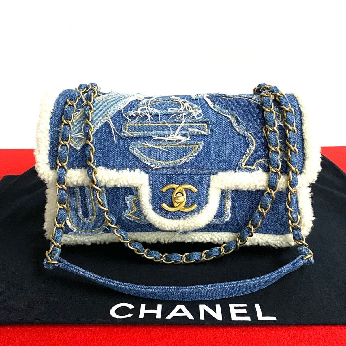 Denim handbag with gold chain strap on a black background, featuring the Chanel logo.