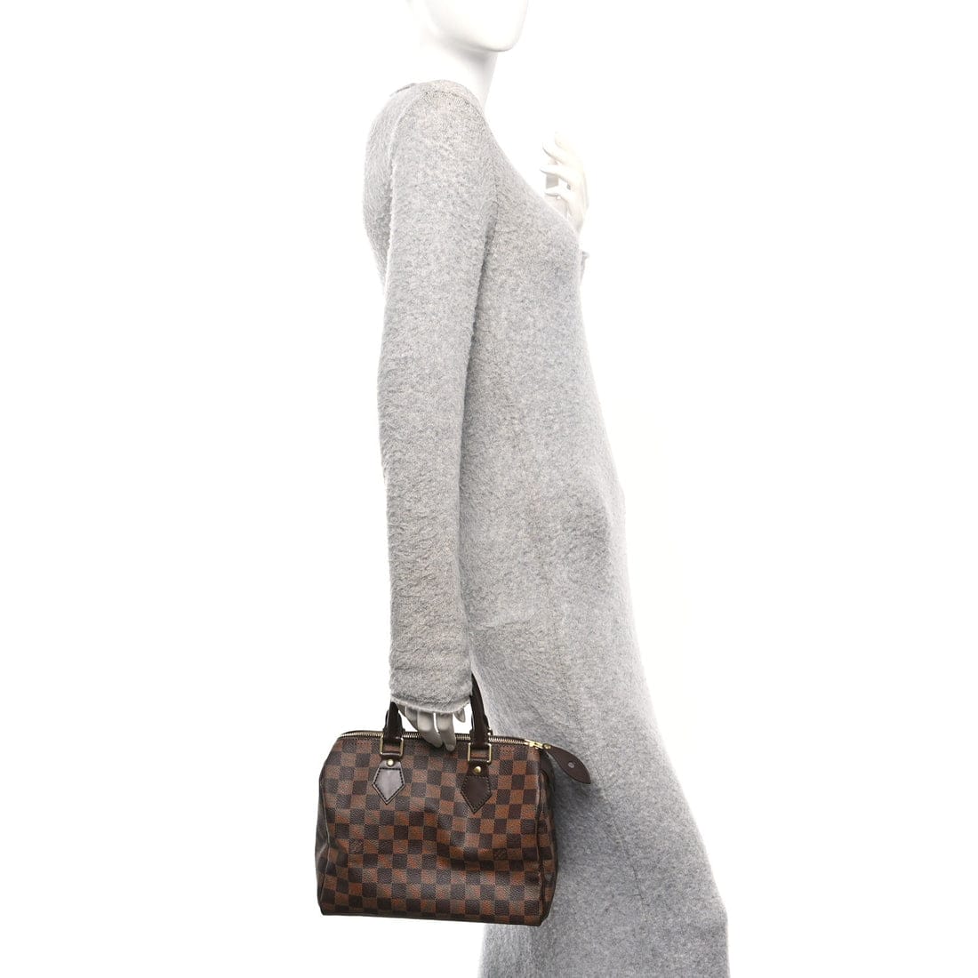 Mannequin wearing a gray sweater holding a brown patterned handbag on a white background