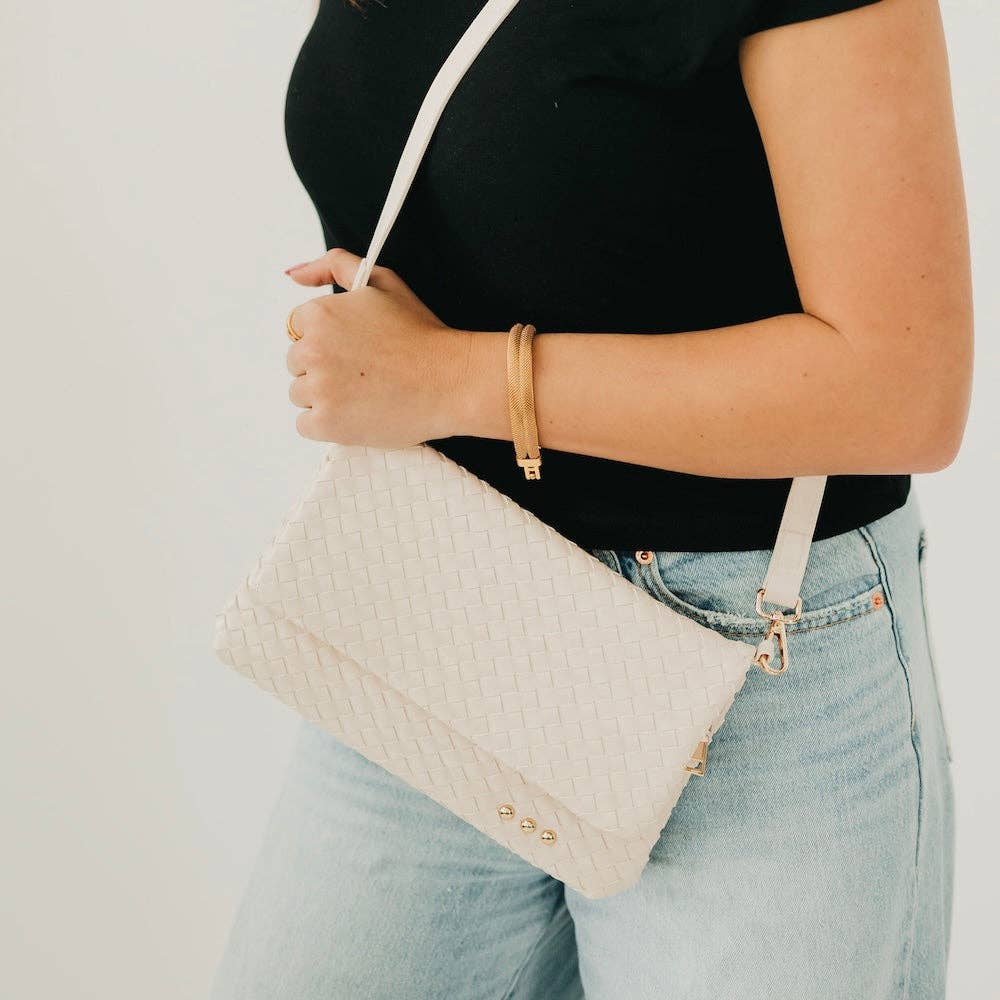 Person holding a beige quilted handbag with a plain background