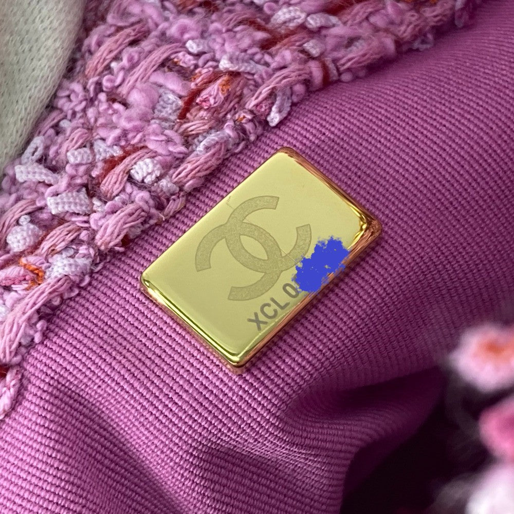 Gold Chanel logo on a pink textured fabric background