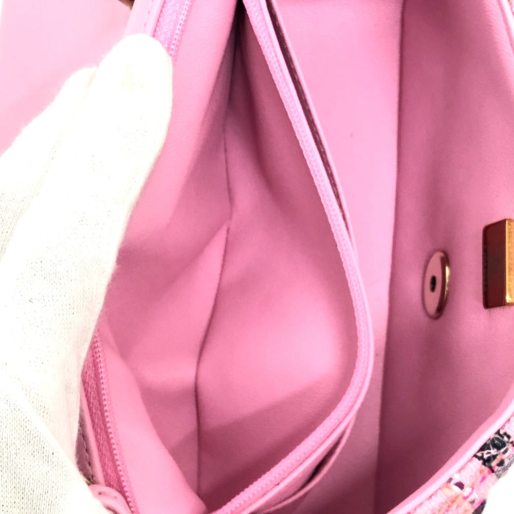 Close-up of a pink bag with a gold button and decorative trim.