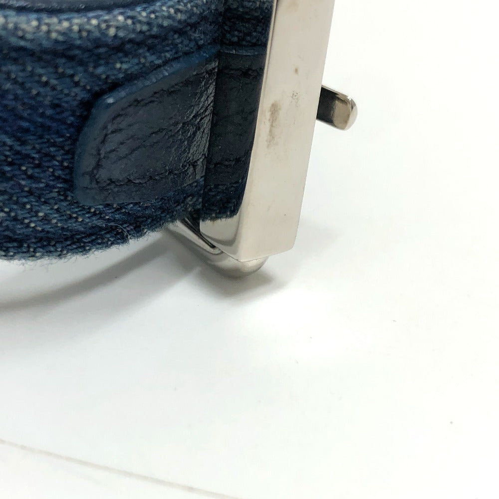 Close-up of a blue denim fabric with a metal buckle on a white background