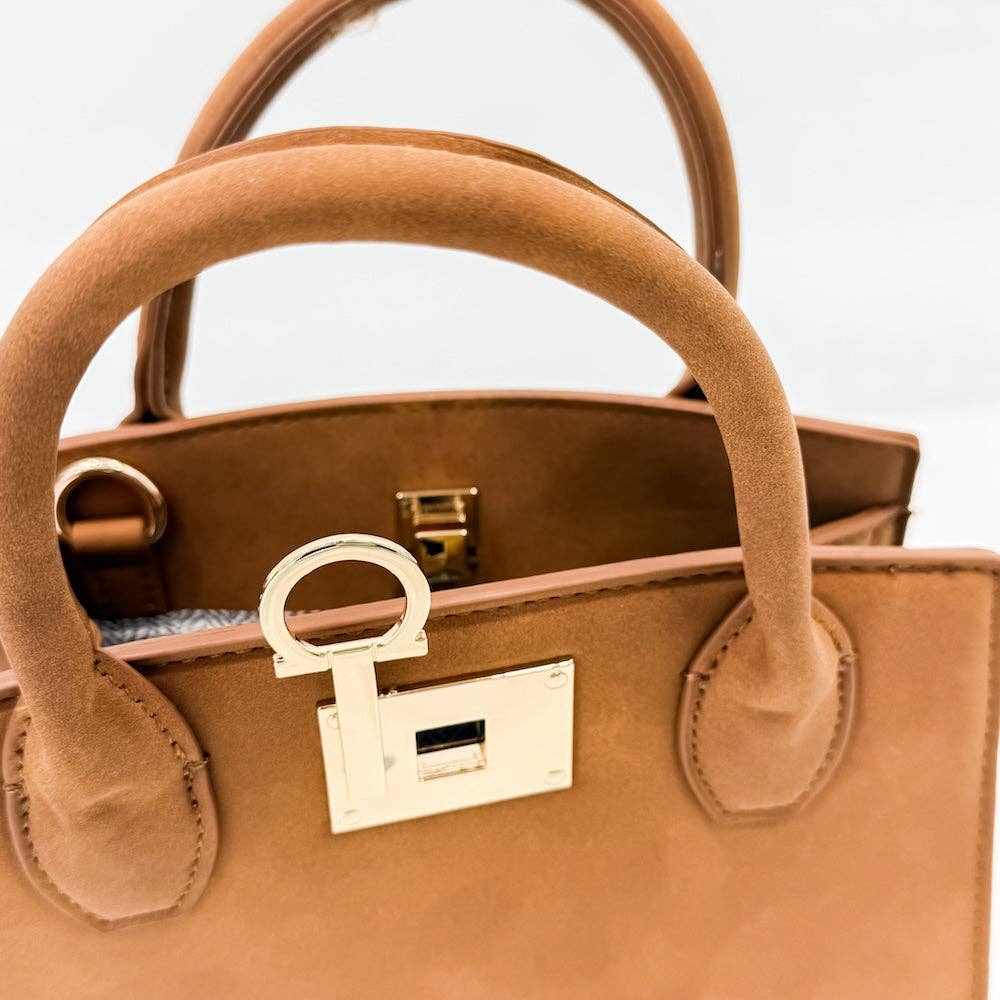 Close-up of a brown handbag with a gold lock on a light gray background