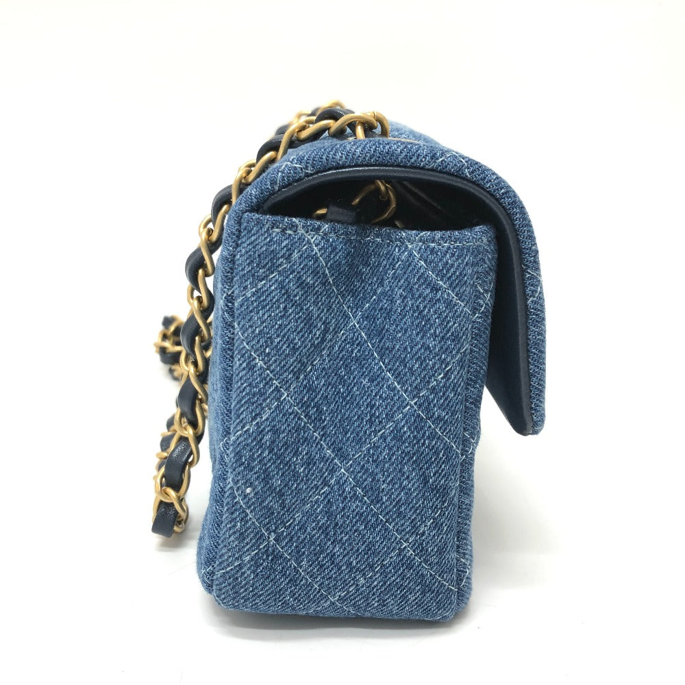 Blue denim handbag with gold chain strap on a white background
