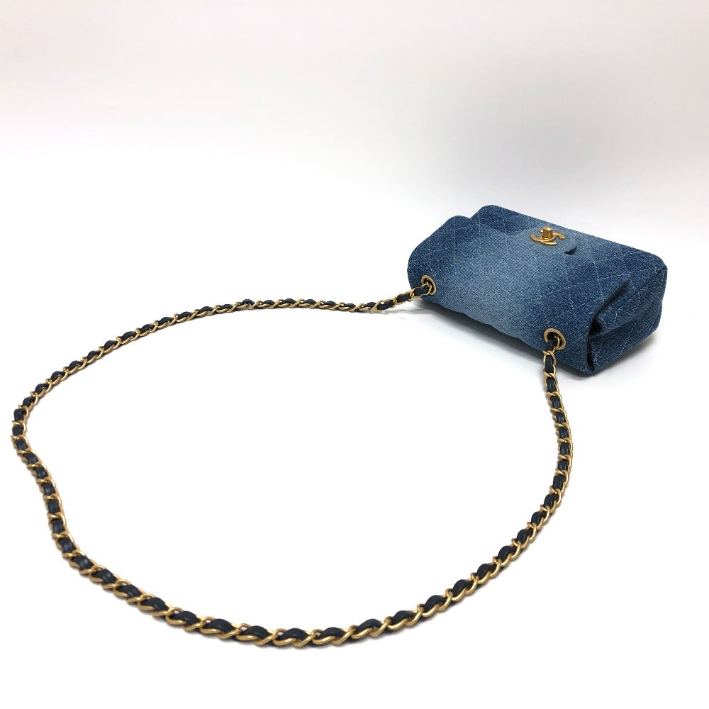Blue denim handbag with gold chain strap on a white background