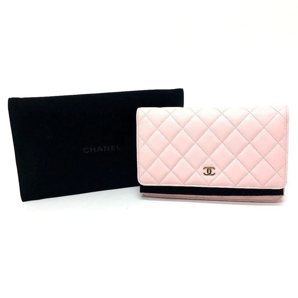 Pink quilted wallet with black Chanel pouch on a white background