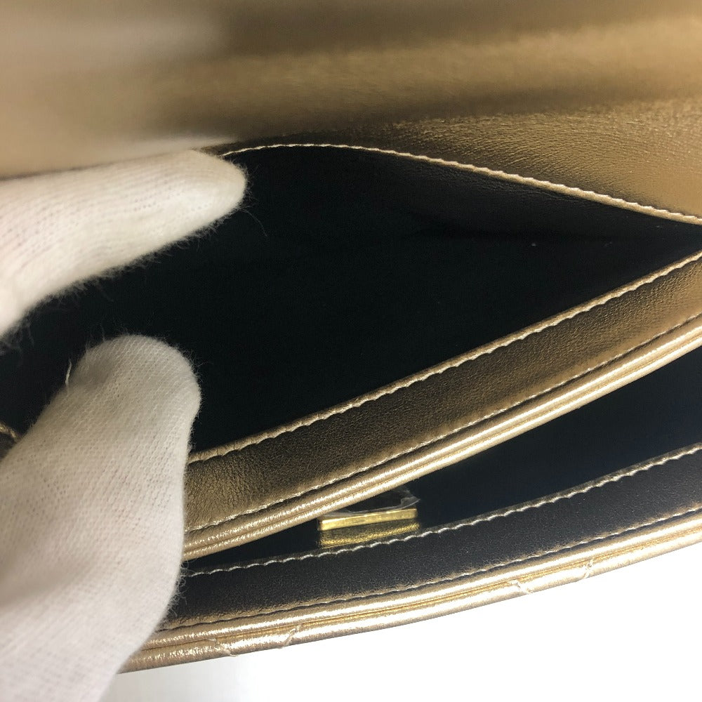 Close-up of a hand holding a black leather wallet with gold stitching.