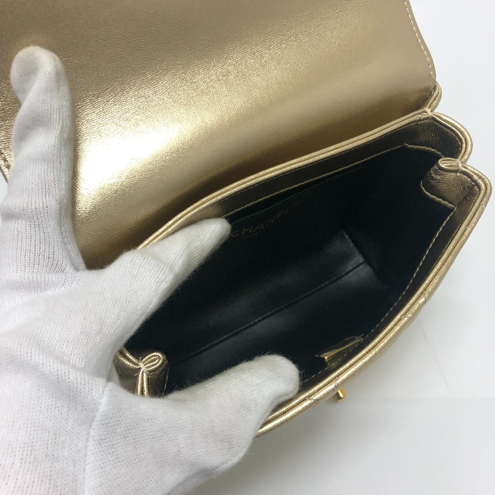Gold clutch bag with a white glove holding it open on a white background