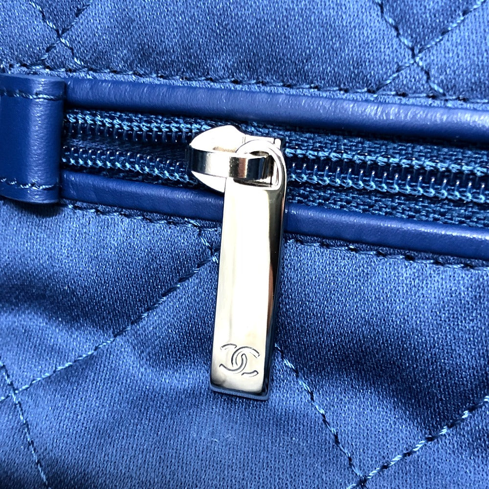 Close-up of a blue quilted handbag with a silver zipper, featuring the Chanel logo.