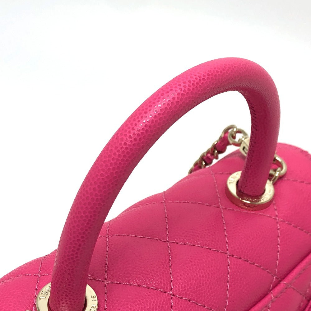Close-up of a pink handbag with quilted design and gold accents on a white background