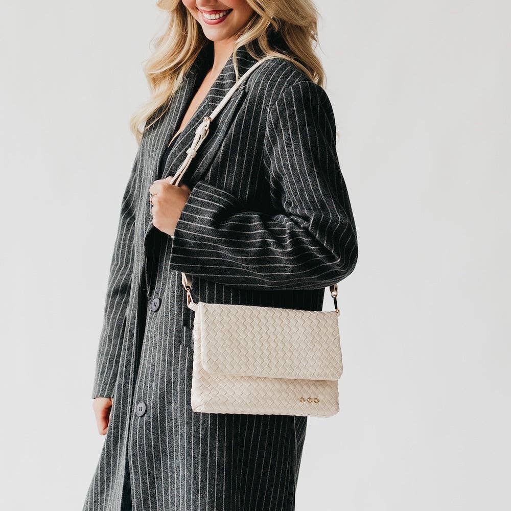 Woman holding a beige quilted handbag against a plain background