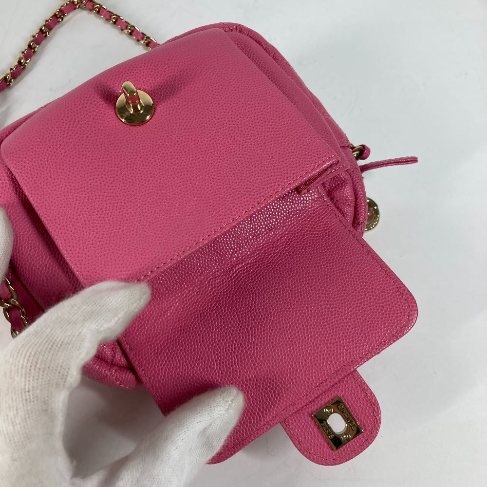 Pink handbag with gold accents held by a gloved hand on a white background