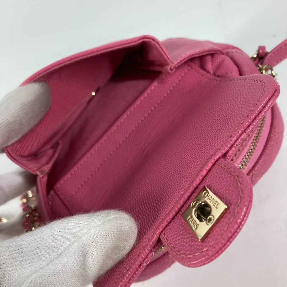 Pink handbag with gold clasp held by a gloved hand on a light pink background