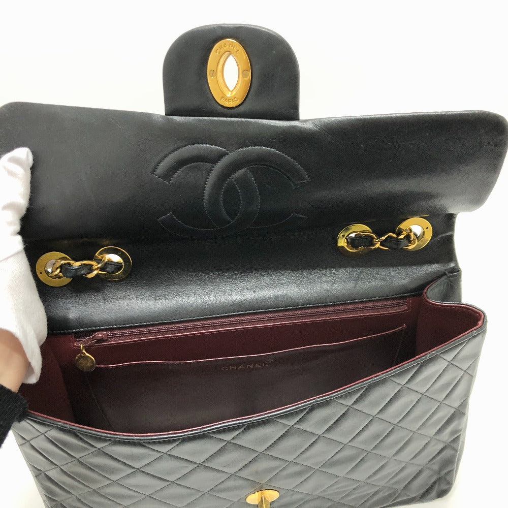 Gray quilted handbag with gold hardware held by a person wearing white gloves.