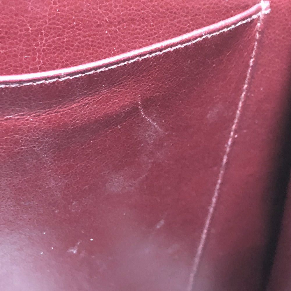 Close-up of a maroon leather surface with visible texture and seam.
