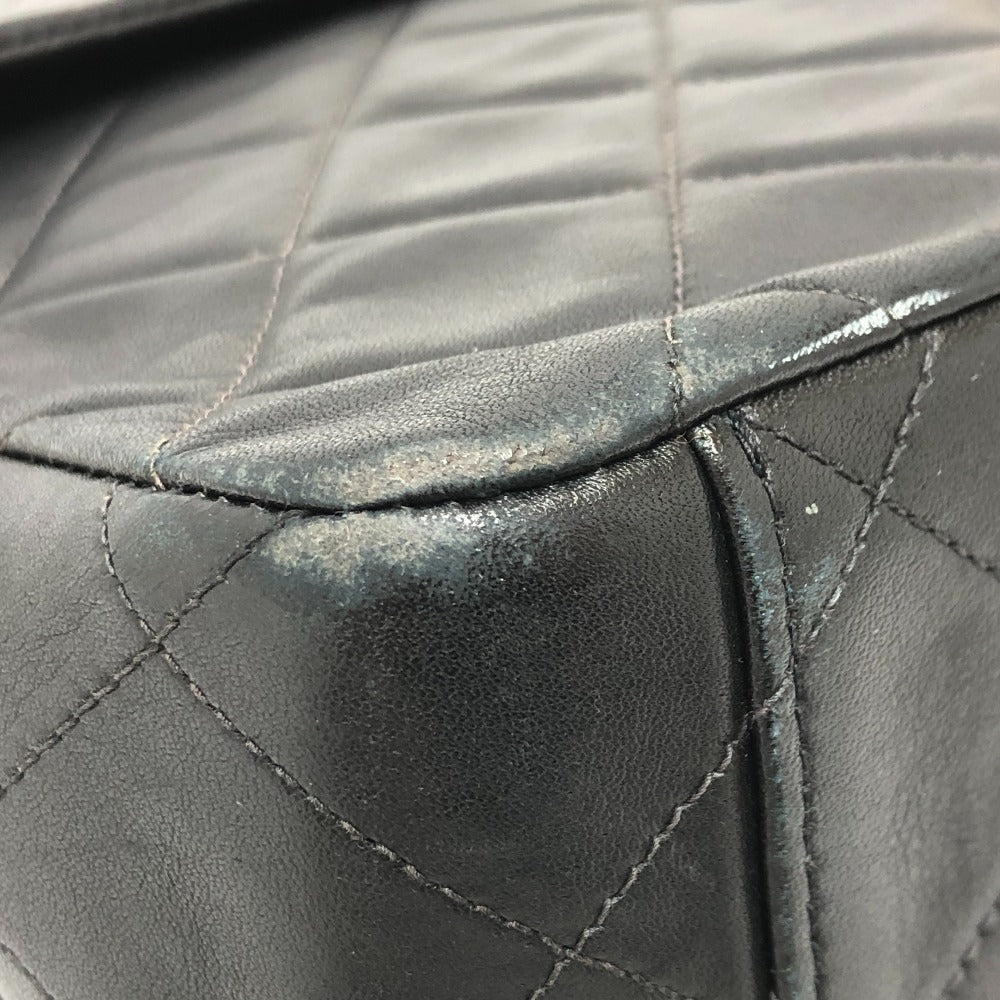 Close-up of a black quilted leather bag with visible wear and tear.