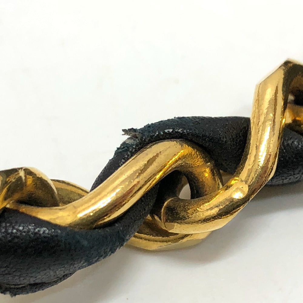 Gold braided bracelet on a black cord against a white background